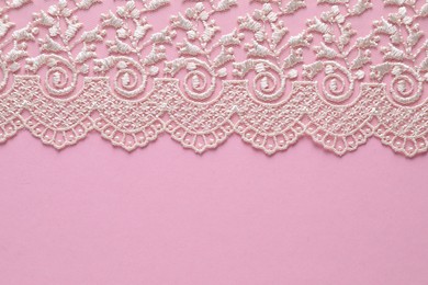 Photo of White lace on pink background, top view. Space for text