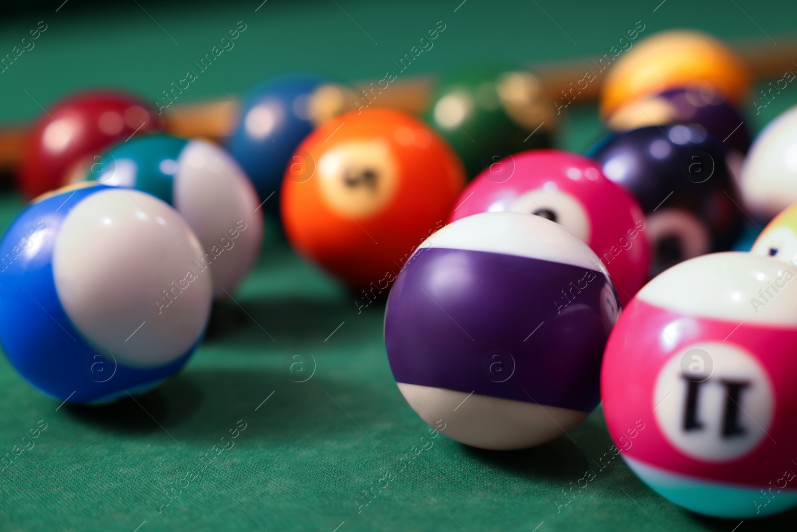 Photo of Many colorful billiard balls on green table, closeup