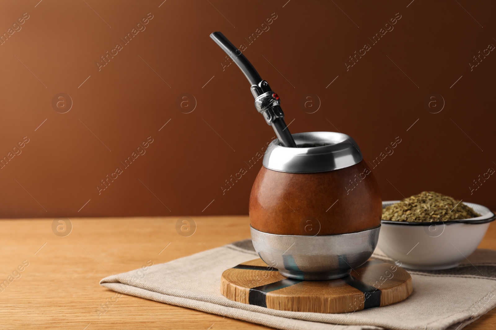 Photo of Calabash with mate tea and bombilla on wooden table. Space for text