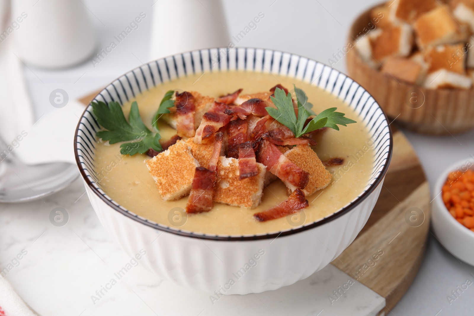 Photo of Delicious lentil soup with bacon and parsley in bowl on table, closeup