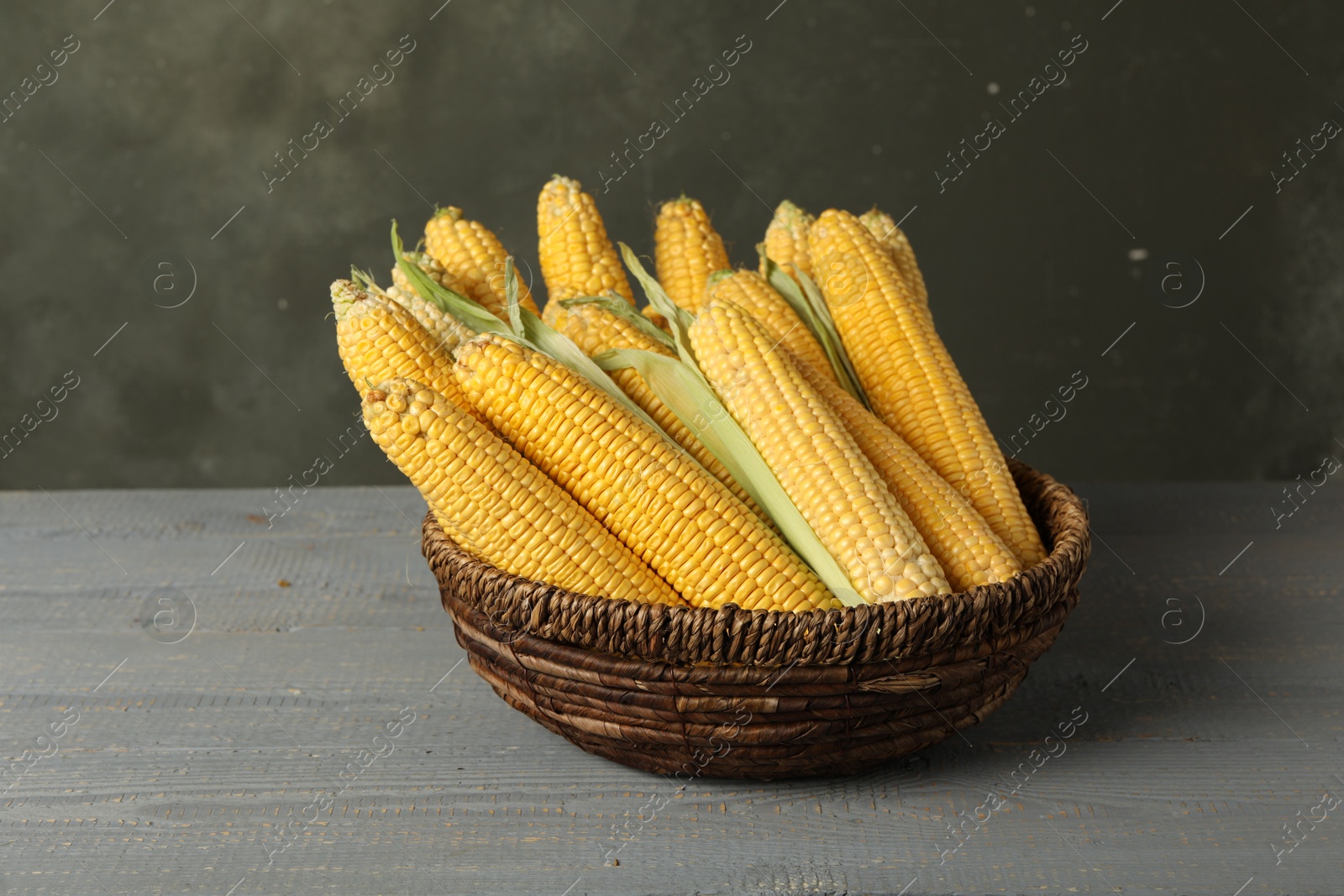 Photo of Corn cobs in bowl on grey wooden table