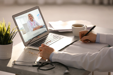 Image of Male medical worker using laptop for online consultation with mature female doctor, closeup 