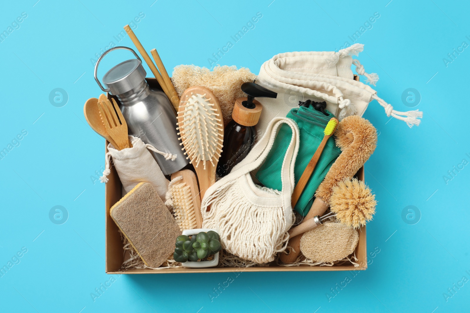 Photo of Cardboard box with eco friendly products on light blue background, top view