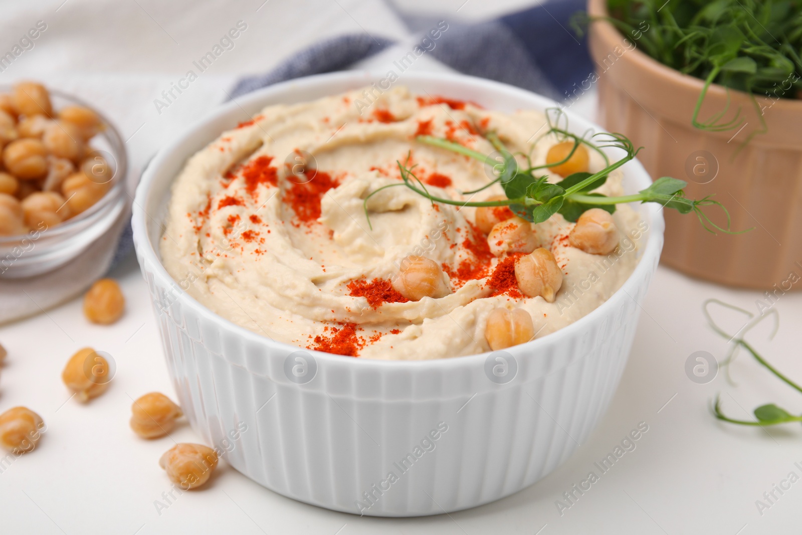 Photo of Delicious hummus with chickpeas and paprika served on white table, closeup