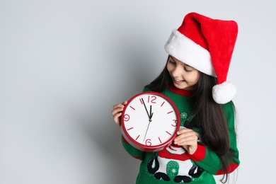 Girl in Santa hat with clock on white background, space for text. Christmas countdown
