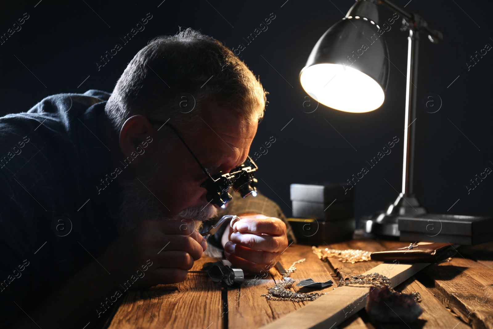 Photo of Male jeweler evaluating diamond ring in workshop