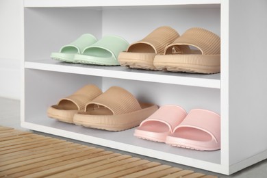 Photo of Storage cabinet with different pairs of rubber slippers indoors