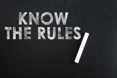 Image of Phrase Know the rules and piece of chalk on blackboard, top view