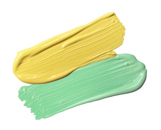 Image of Strokes of green and yellow color correcting concealers on white background, top view