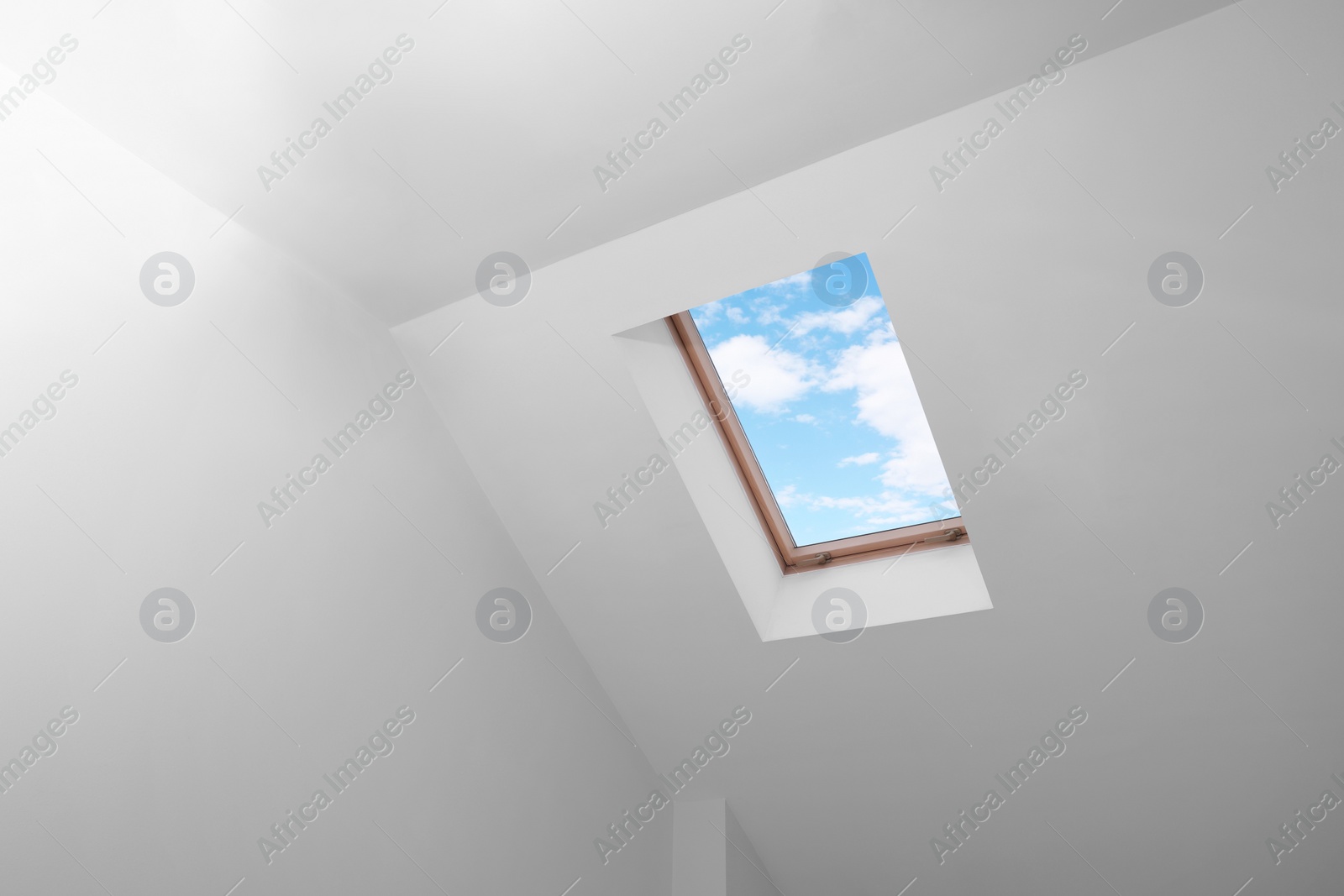 Photo of Skylight roof window and lamps on slanted ceiling in attic room, low angle view