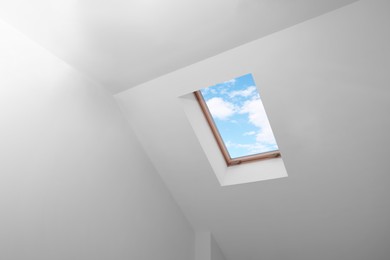 Photo of Skylight roof window and lamps on slanted ceiling in attic room, low angle view