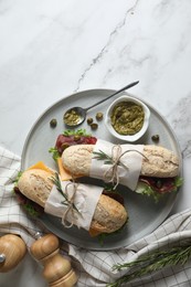 Photo of Delicious sandwiches with bresaola, cheese and lettuce served on white marble table, flat lay. Space for text