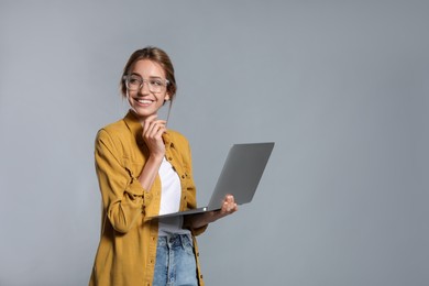 Photo of Portrait of young woman with modern laptop on grey background. Space for text