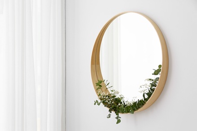 Photo of New round mirror in wooden frame on white wall, space for text. Idea for interior design