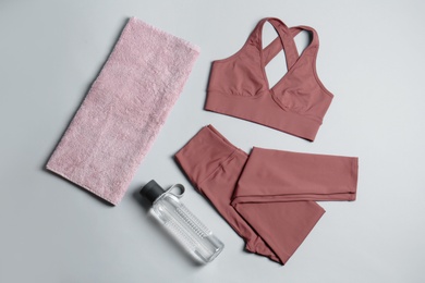 Photo of Sportswear, bottle of water and towel on grey background, flat lay. Yoga equipment