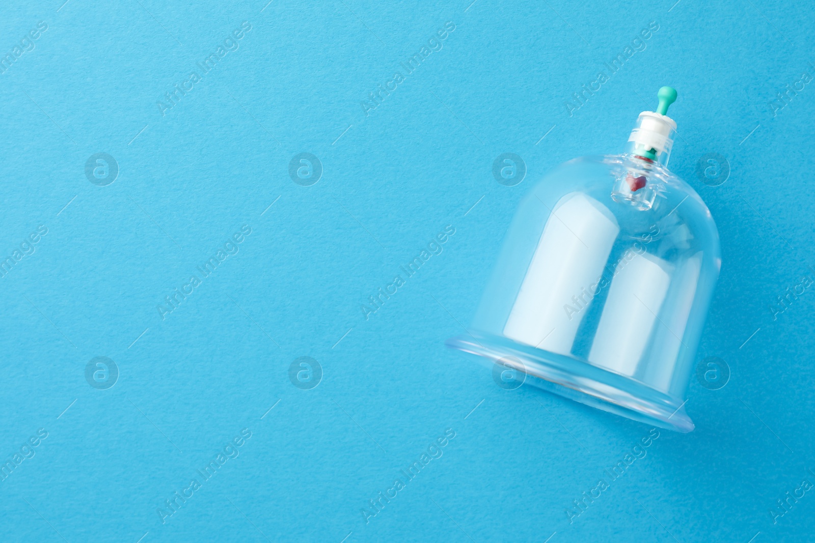 Photo of Plastic cup on light blue background, top view with space for text. Cupping therapy