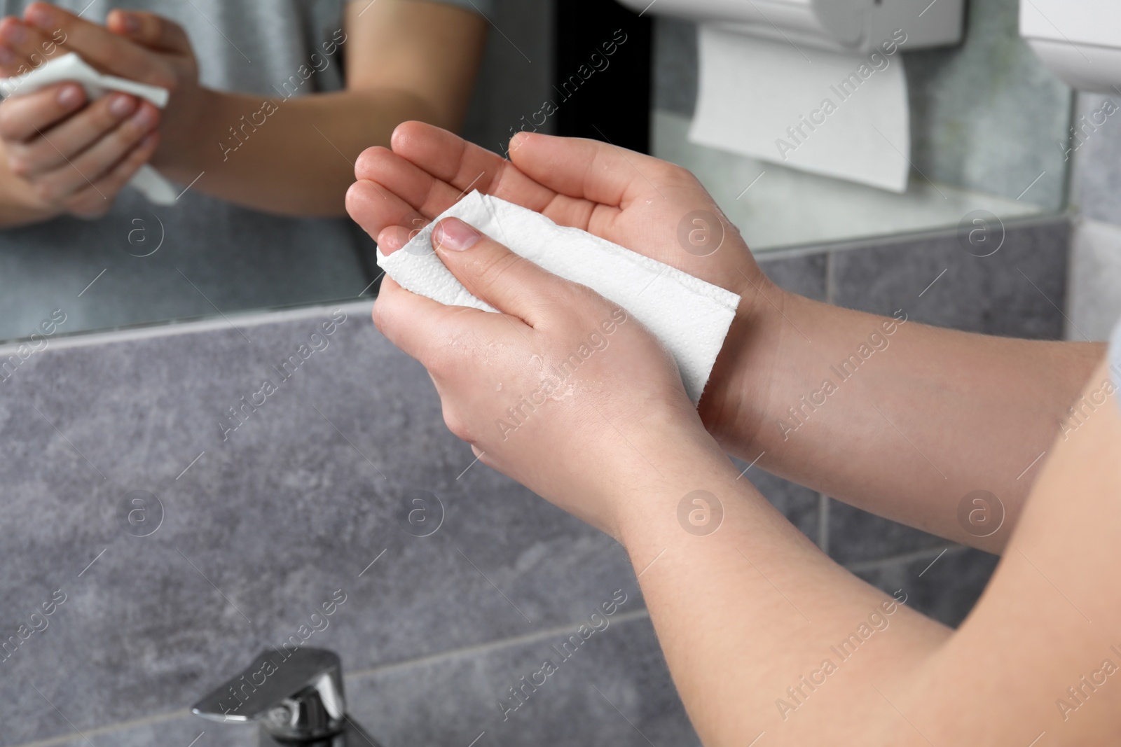 Photo of Woman wiping hands with paper towel in bathroom, closeup