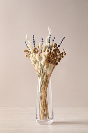 Photo of Dried flowers in vase on table against light background
