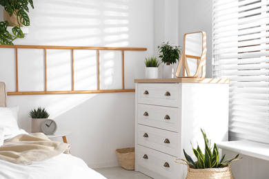 Photo of White chest of drawers in beautiful bedroom. Interior design