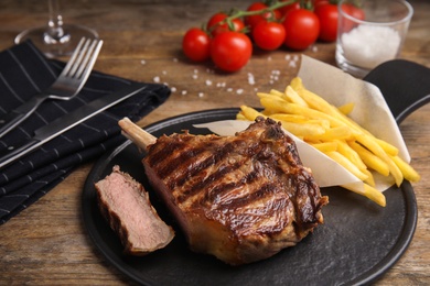 Tasty grilled beef steak and French fries on wooden table