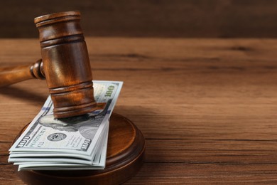 Photo of Judge's gavel and money on wooden table. Space for text