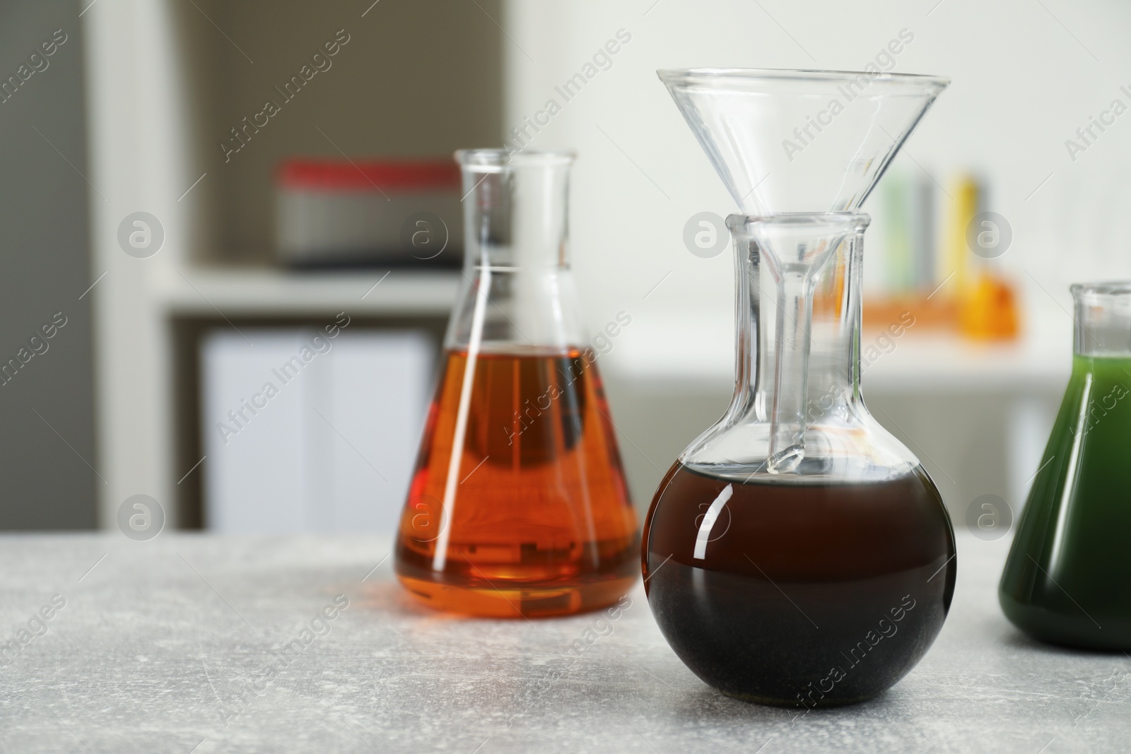 Photo of Laboratory glassware with different types of crude oil on light grey table, space for text