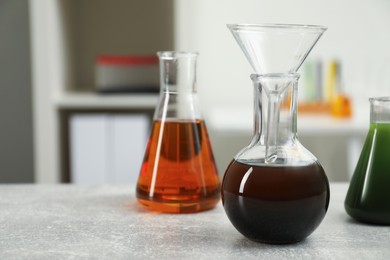 Laboratory glassware with different types of crude oil on light grey table, space for text