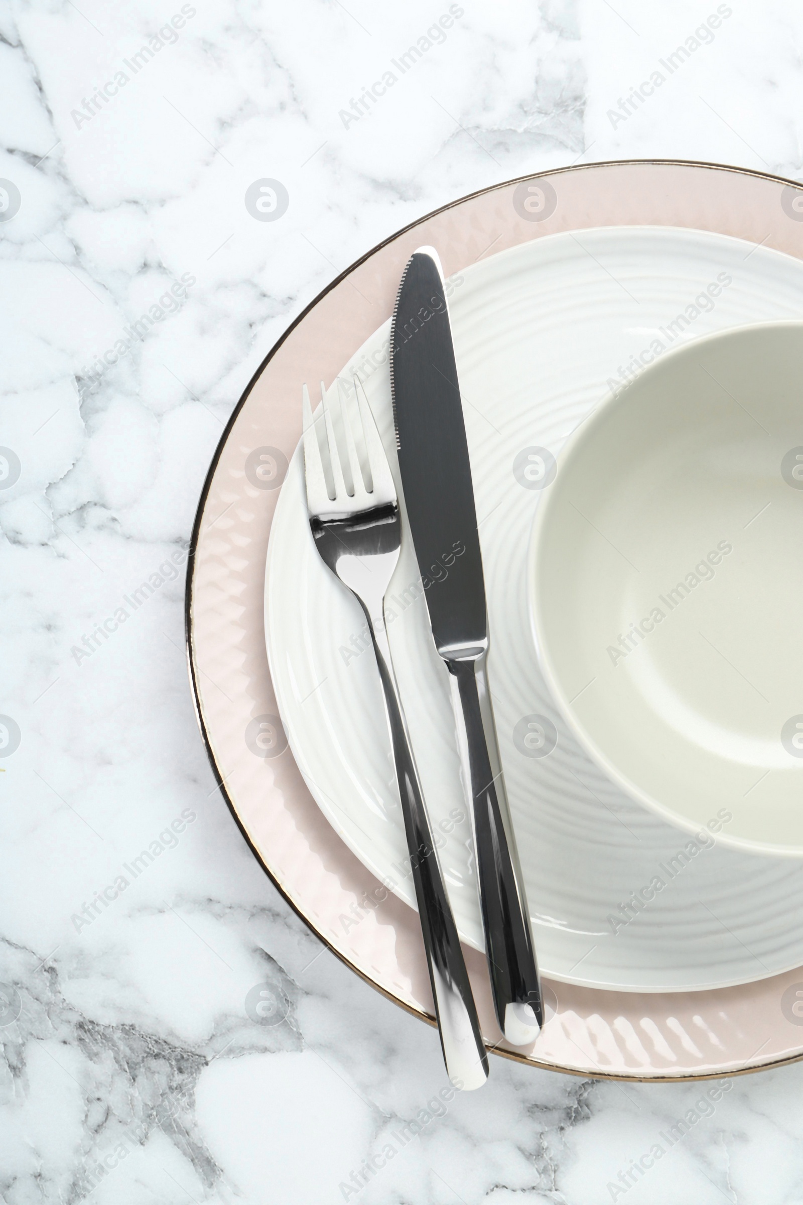 Photo of Clean plates, bowl and cutlery on white marble table, top view