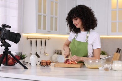 Photo of Food blogger cooking while recording video in kitchen
