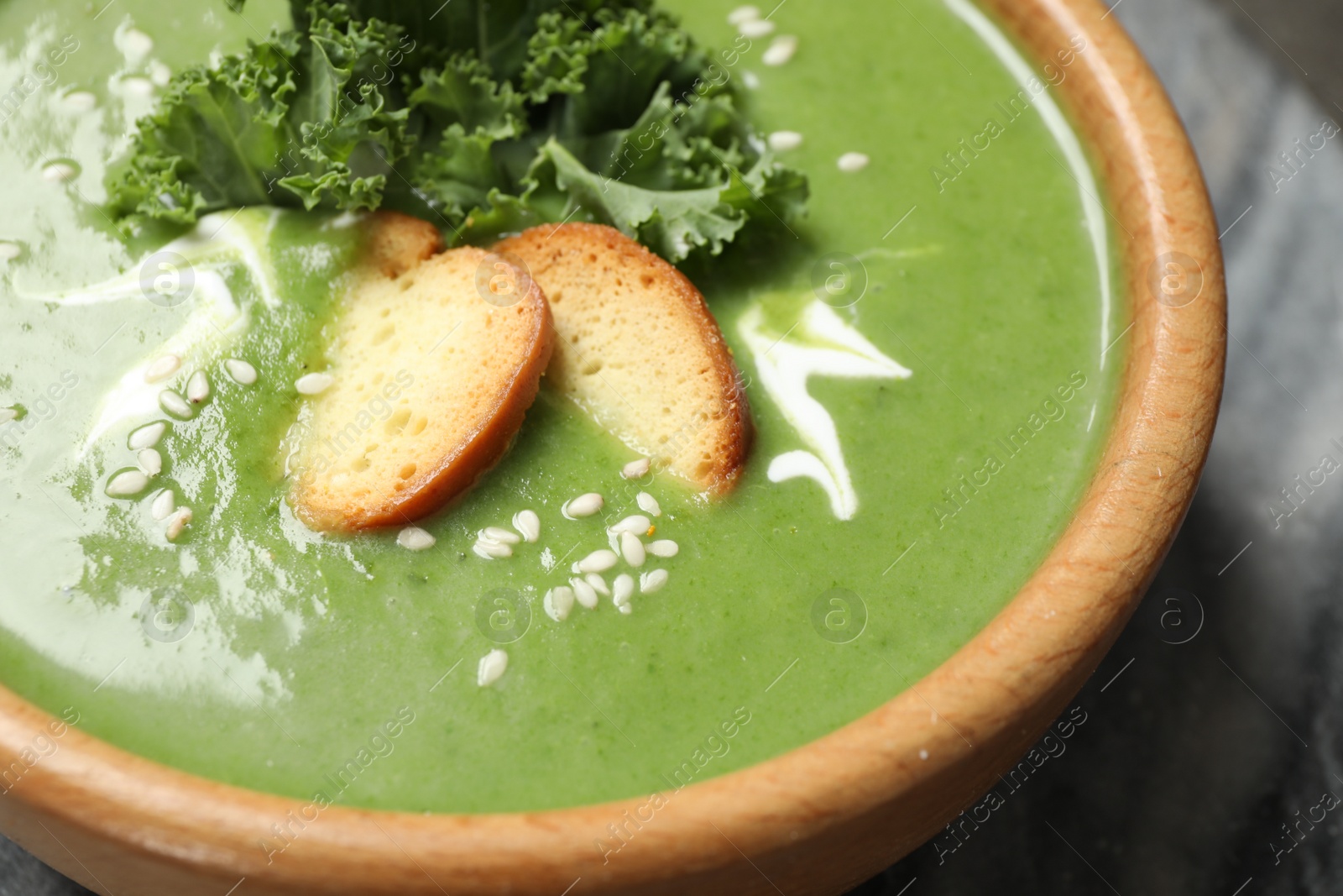 Photo of Tasty kale soup with croutons on grey marble table, closeup