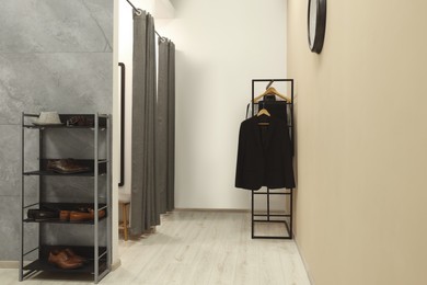 Photo of Dressing room with clothing rack in fashion store. Stylish design