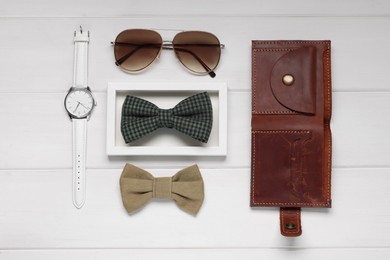 Photo of Stylish color bow ties, sunglasses, wallet and wristwatch on white wooden background, flat lay