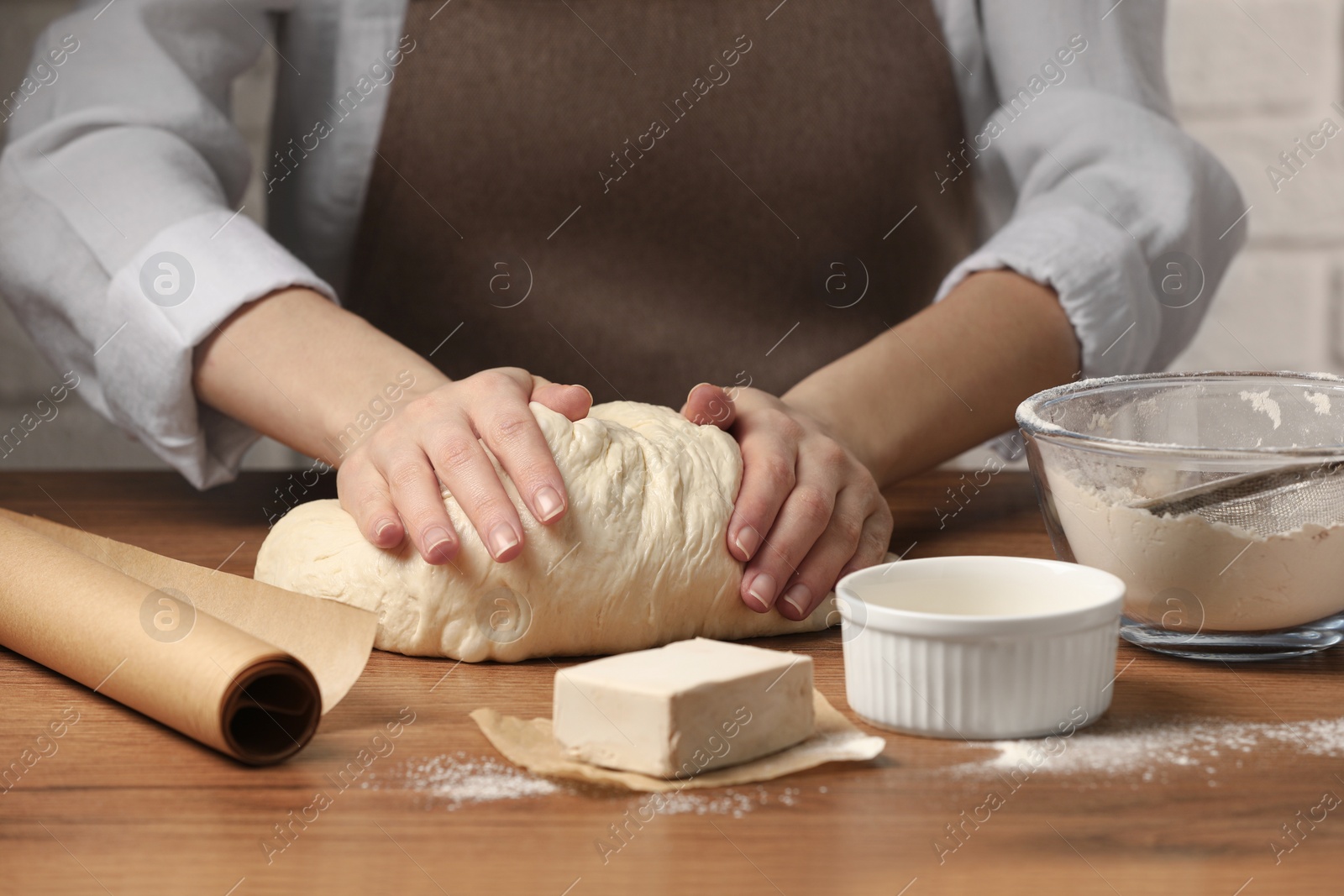 Photo of Woman kneading yeast dough for cake at wooden table, closeup