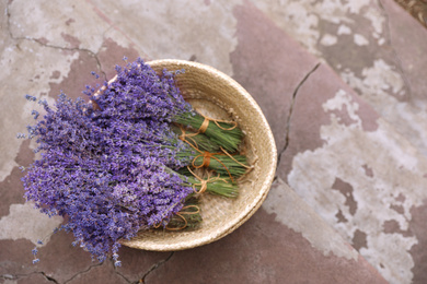 Wicker basket with lavender flowers on cement floor outdoors, top view. Space for text