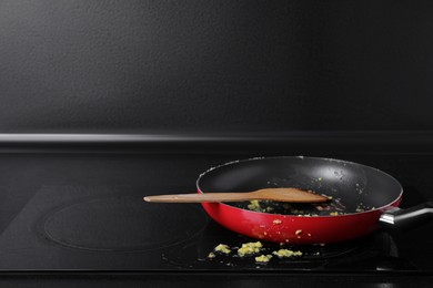 Dirty frying pan with spatula on cooktop in kitchen, space for text