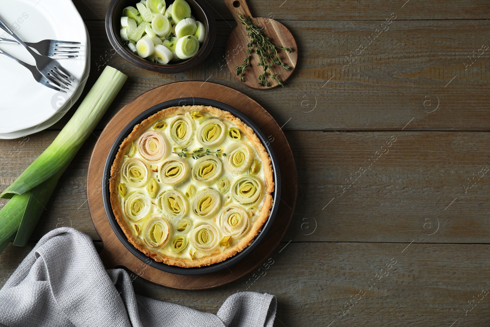 Photo of Flat lay composition with tasty leek pie and ingredients on wooden table. Space for text