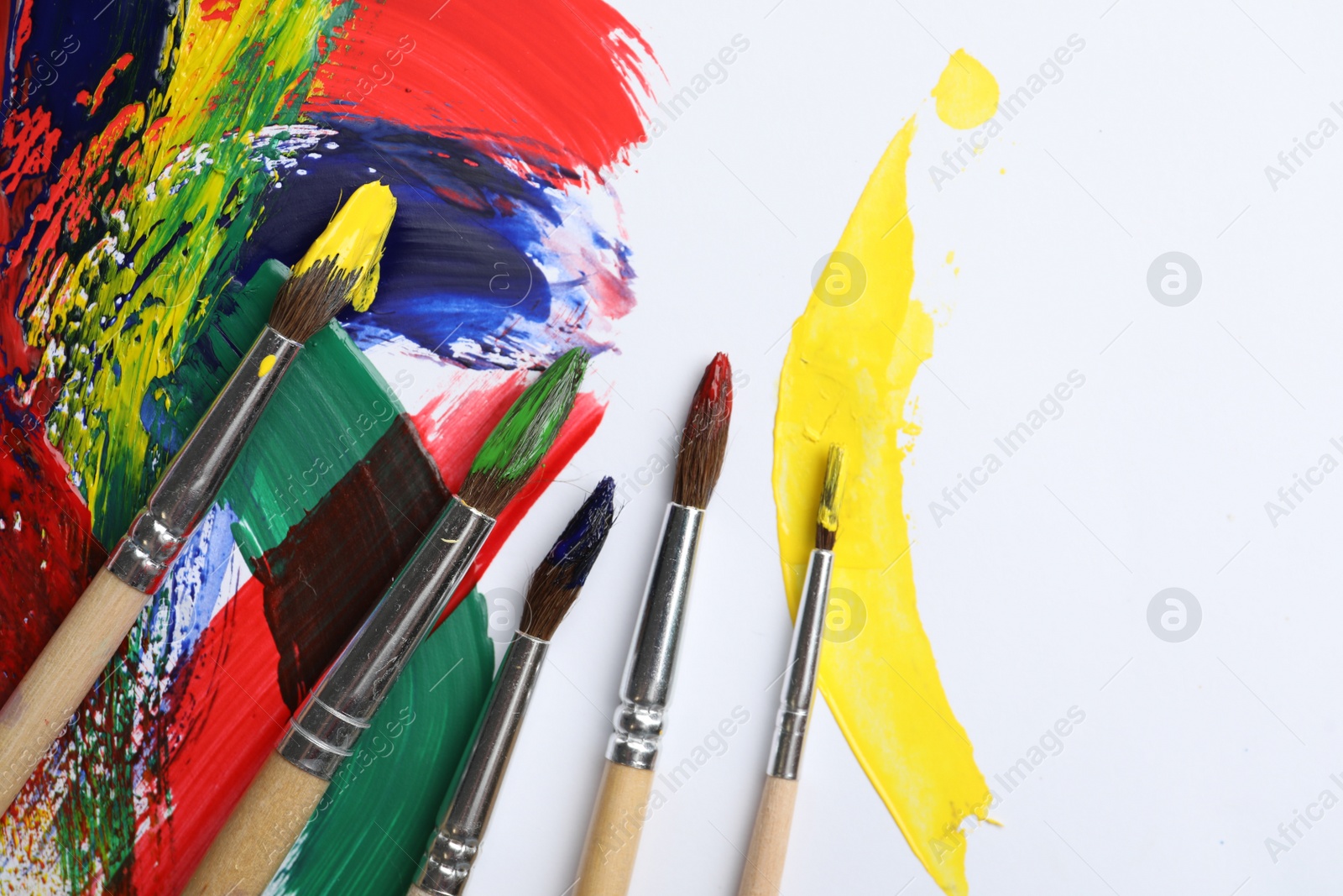 Photo of Brushes with different paints and strokes on white background, flat lay