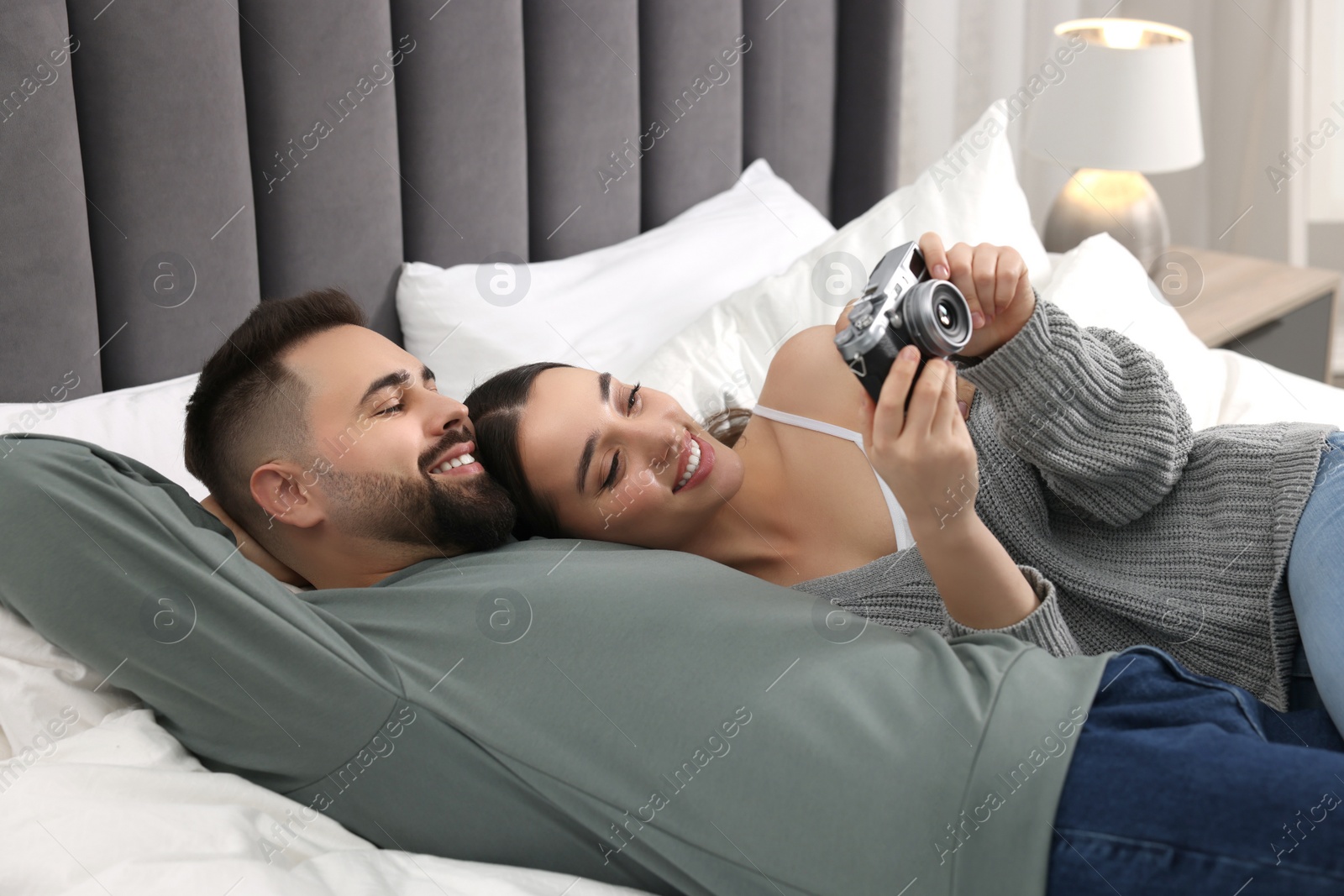 Photo of Happy young couple with camera on bed