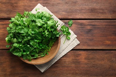 Photo of Fresh coriander in bowl on wooden table, top view. Space for text