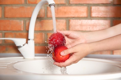 Photo of Woman washing fresh nectarines in kitchen sink, closeup