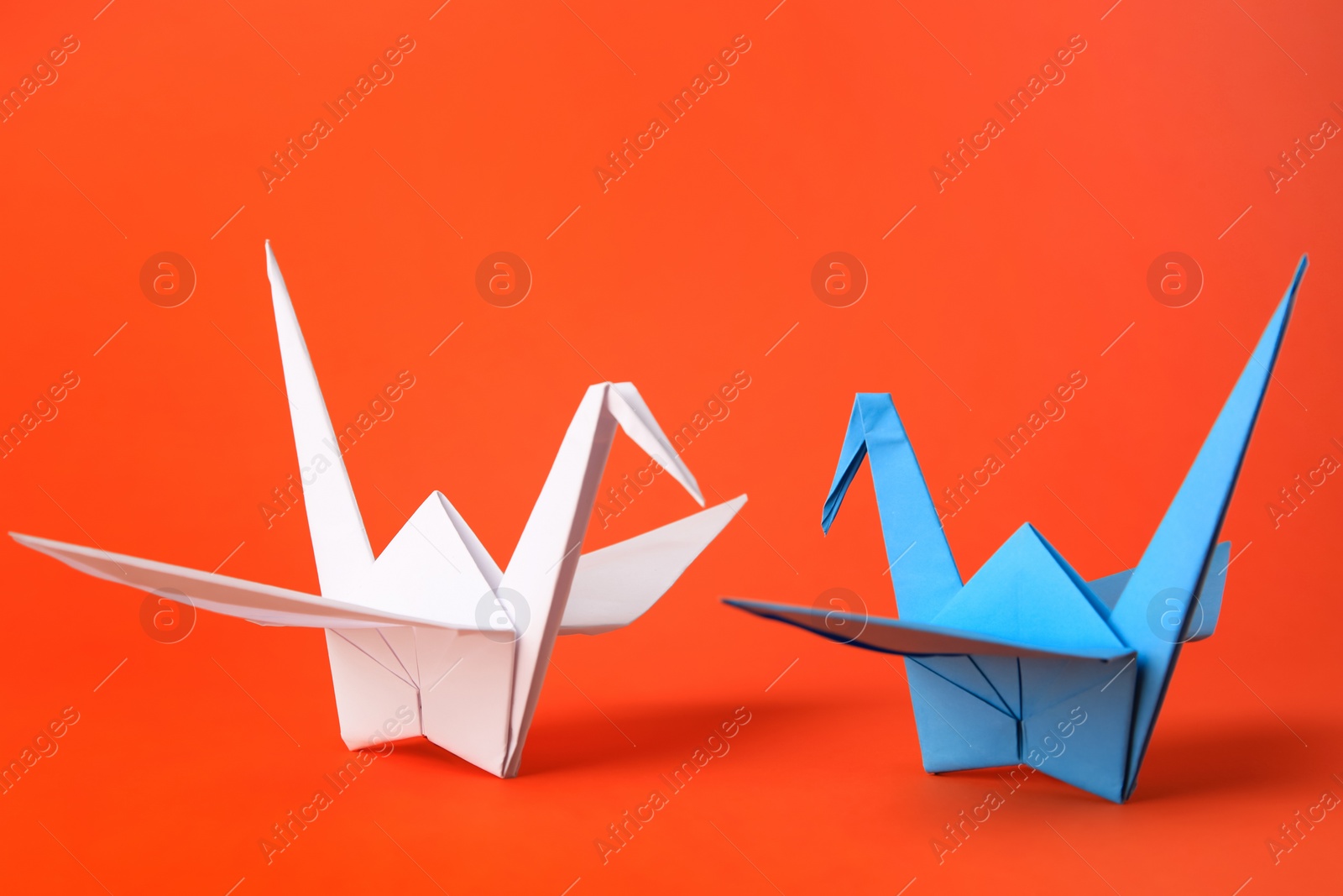 Photo of Colorful paper origami cranes on orange background, closeup