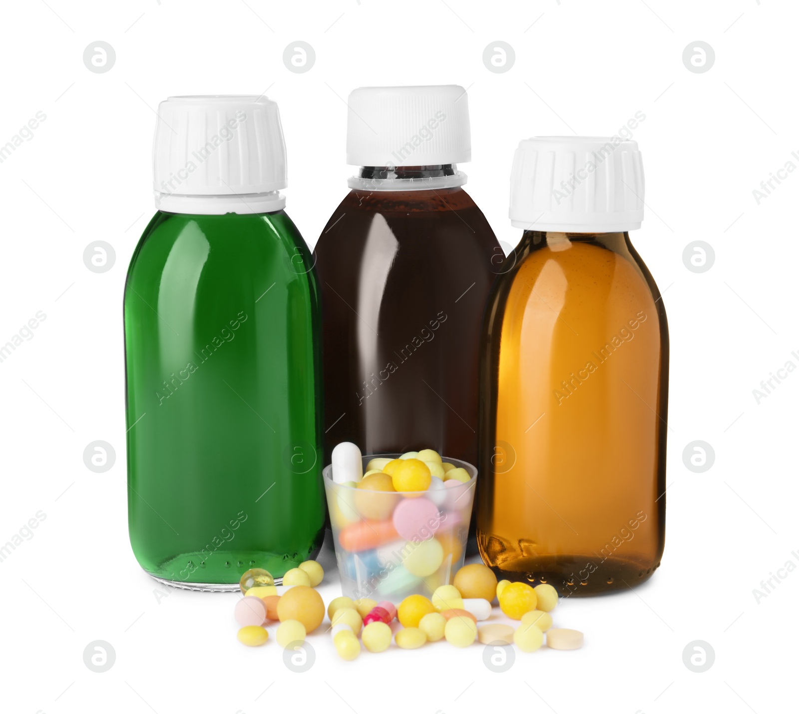 Photo of Bottles of syrups, measuring cup with pills on white background. Cough and cold medicine