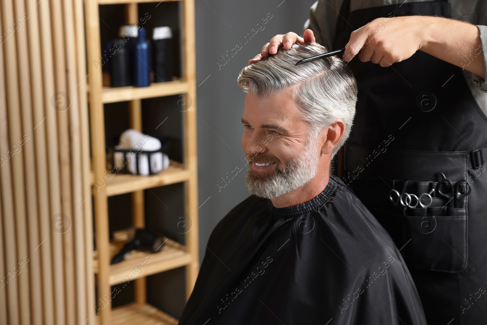 Photo of Hair styling. Professional hairdresser working with happy client in barbershop, closeup