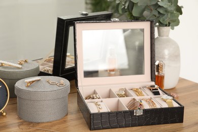 Elegant jewelry box with beautiful bijouterie and expensive wristwatches near luxury perfume on wooden table