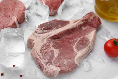 Photo of Fresh raw cut beef and ice cubes on white table, closeup