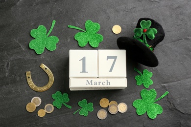 Photo of Leprechaun's hat, block calendar and St. Patrick's day decor on black background, flat lay
