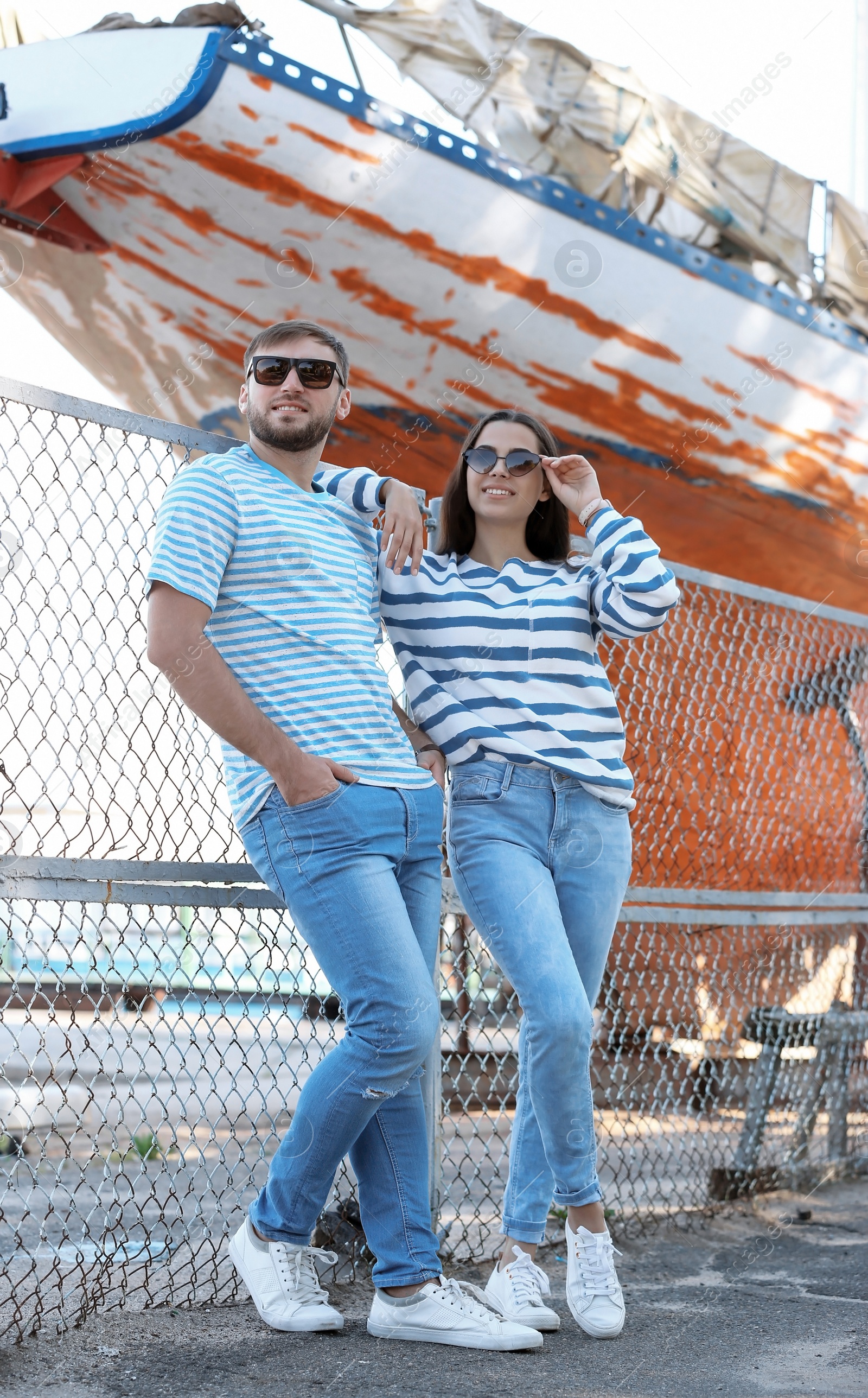 Photo of Young hipster couple in stylish jeans on pier