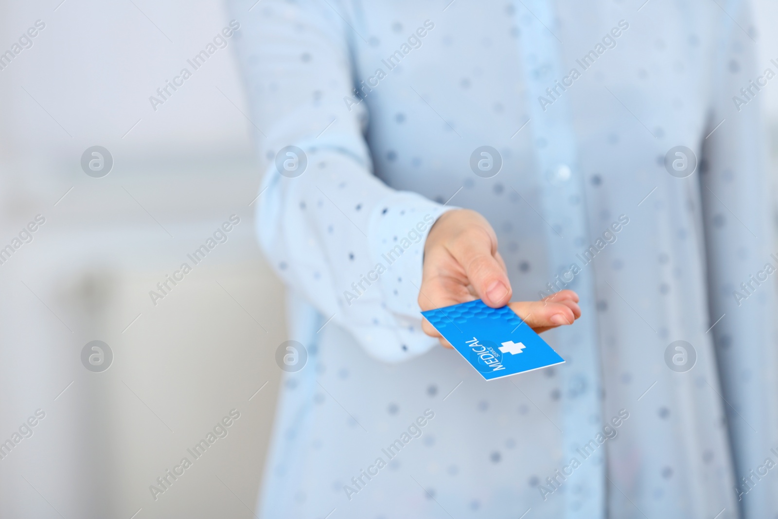 Photo of Woman holding business card indoors, closeup with space for text. Medical service