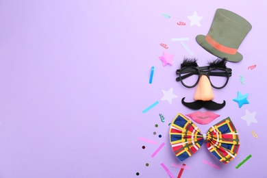 Flat lay composition with clown's face made of party glasses, cylinder and bow tie on violet background. Space for text