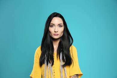 Portrait of young hippie woman with boho makeup in stylish outfit on color background